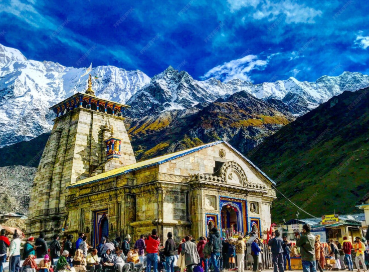 Kedarnath Temple with snow-covered Himalayan peaks in the background, Devotees visiting Kedarnath Temple in Uttarakhand on a sunny day. Sacred Kedarnath Temple surrounded by majestic Himalayan mountains. Kedarnath Temple pilgrimage site with clear blue sky and devotees. Ancient Kedarnath Temple in the Garhwal Himalayas of India. Spiritual view of Kedarnath Temple with snow-capped peaks behind. Kedarnath Temple entrance with worshippers and mountain scenery. Famous Kedarnath Temple in Uttarakhand during pilgrimage season.