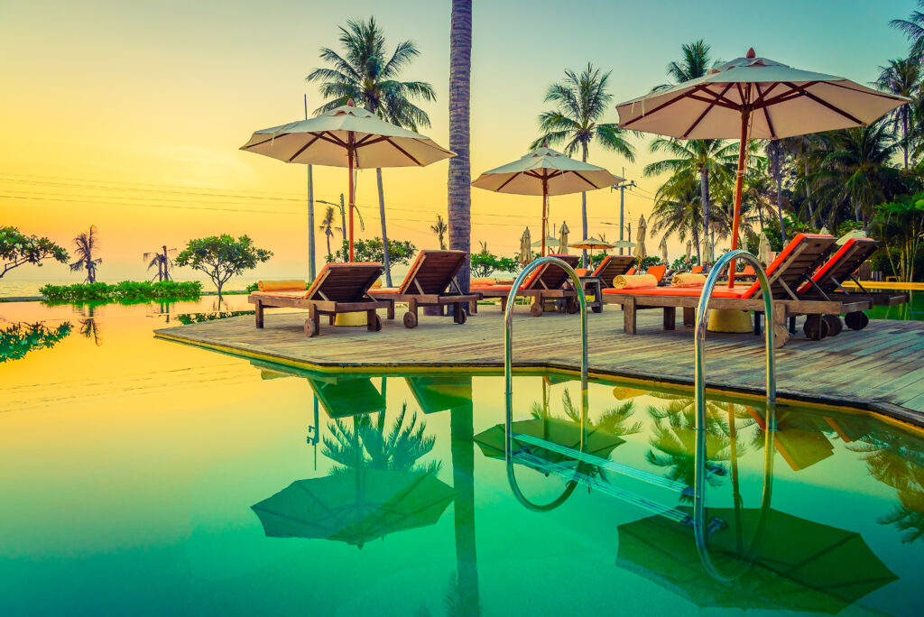 luxury pool sunset, tropical beach resort, infinity pool view, palm trees sunset, summer holiday vibes, exotic travel destination, seaside relaxation spot, tropical vacation escape, paradise beach sunset, resort poolside chairs