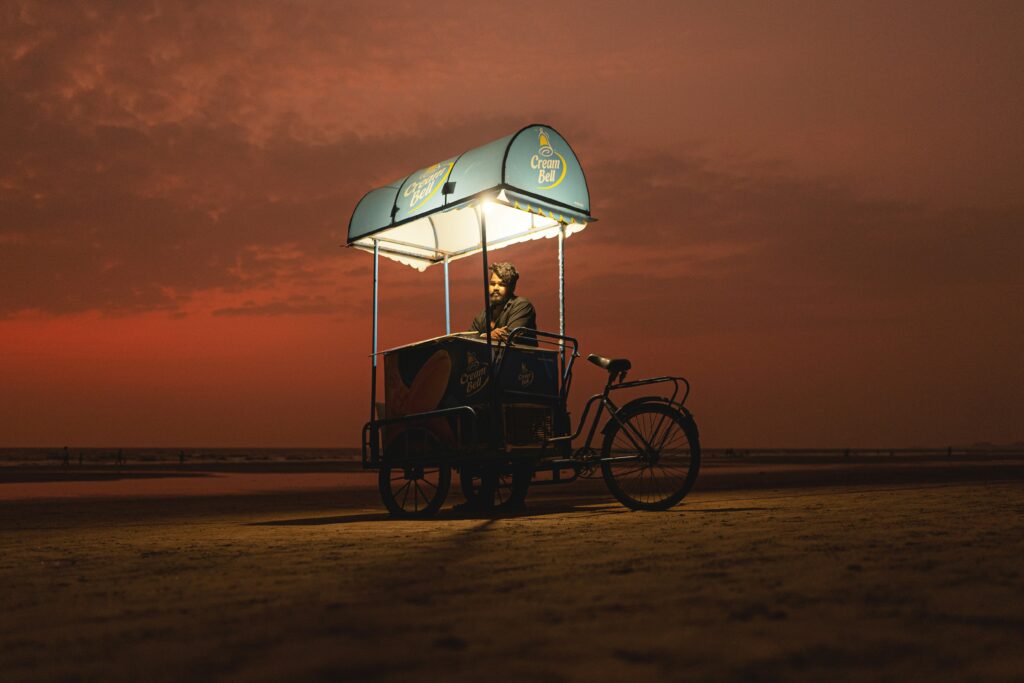 Ice Cream Cart Sunset Beach Vendor Dusk Street Food Cycle Cart Man Selling Ice Cream Fiery Red Sky Beach Illuminated Food Stall Night Market Vendor Cream Bell Cart Tricycle Food Stand Single Vendor Portrait
