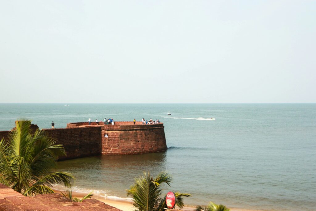 Fort Aguada Goa Historic Fort Sea Red Laterite Fort Wall Goa Tourism Sight Indian Ocean View Palm Trees Fort Coastal Defense Structure Portuguese Fort Ruins Beach Fortification Old Fort Wall View