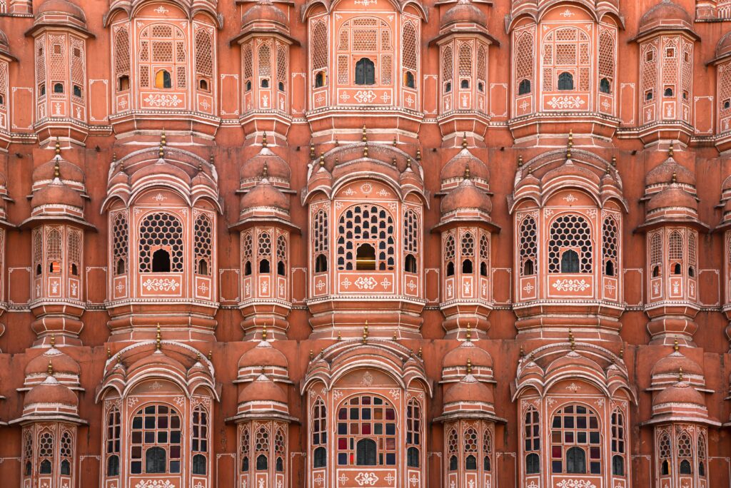 Hawa Mahal Facade Detail Jaipur Pink Sandstone Intricate Jharokha Windows Palace of Winds Close-up Rajput Architecture Pattern Historical Building India Symmetrical Palace Facade Pink City Landmark Detail Indian Mughal Windows Ornate Wall Texture