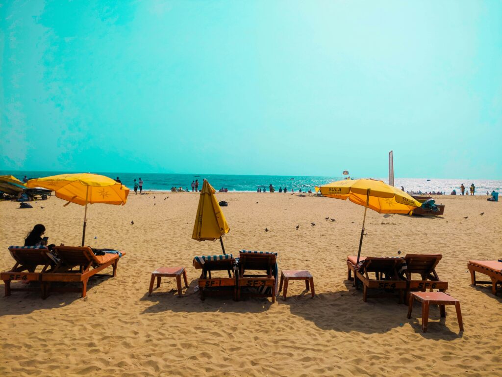 Beach Chairs Yellow Umbrella Sandy Beach Loungers Goa Beach Tourism Tropical Beach Relaxation Sunbeds Ocean View Sula Beach Shacks (Based on visible logo) Crowded Beach Landscape Clear Blue Sky Coast Beachfront Rental Chairs Indian Beach Vacation