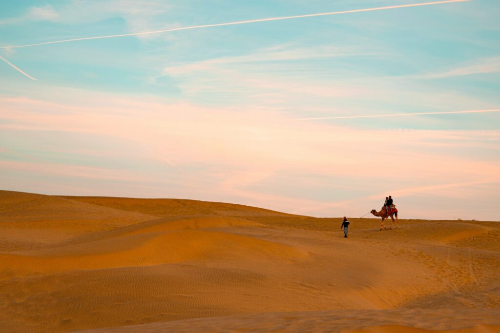 camel safari rajasthan desert sunset thar desert dunes travel india golden sand dunes dramatic sky jaisalmer desert landscape camel ride travel adventure india desert safari monaal garg desert photography serene desert view dusk soft light tourists riding camel on sand dunes desert exploration travel destination sunrise sunset desert vibrant colors